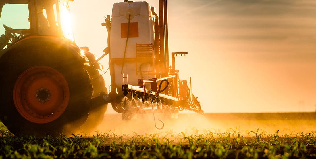 Um maquinário agrícola jogando defensivos agrícolas na plantação.